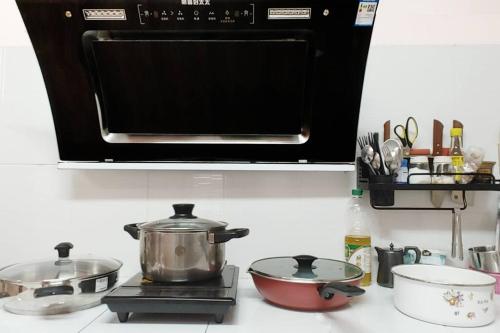a microwave above a stove with pots and pans at 曼谷辉煌 旺中带静 带庭院的3个房间独立别墅 in Bang Rak