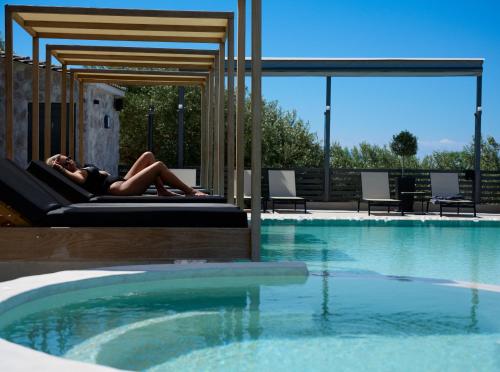 a woman laying on a bed next to a swimming pool at Irene Studios in Pefki