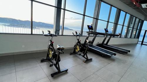 a gym with three exercise bikes in a room with windows at JQ Unity Homestay 2 High Floor Seaview Netflix 6pax in Kota Kinabalu