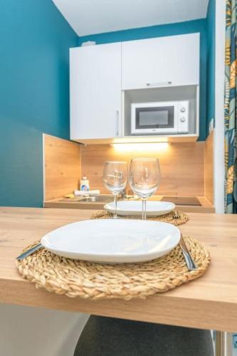 - une table avec deux assiettes et des verres à vin dans l'établissement Studio moderne et cosy à 700m de la gare, à Grenoble