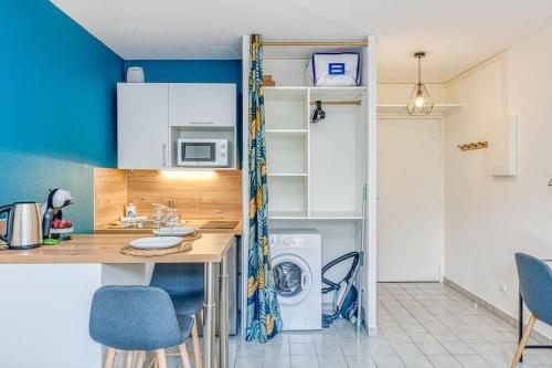 une cuisine avec des murs bleus et un comptoir avec une machine à laver dans l'établissement Studio moderne et cosy à 700m de la gare, à Grenoble