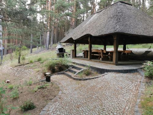 a pavilion with a table and a straw roof at Apartament na skarpie z widokiem na jezioro Swornegacie in Swornegacie 