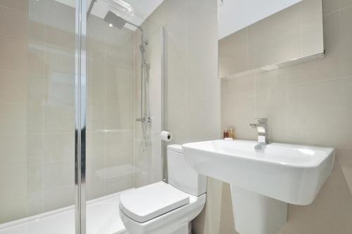 Un baño con lavabo, inodoro y ducha. en Access West Kensington, en Londres