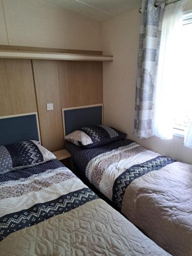 two beds in a room with a window at Camping de Zandhorst, Chalet Victory in Wouterswoude
