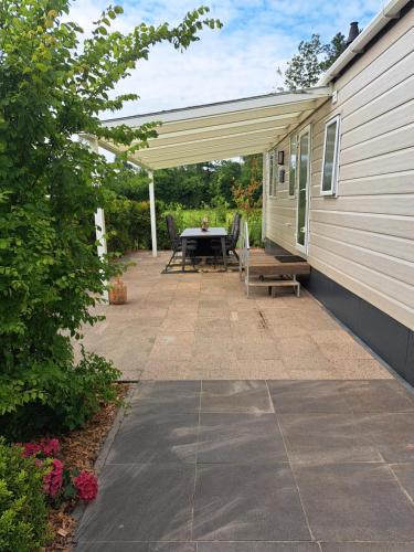 a patio with a table and a bench next to a house at Camping de Zandhorst, Chalet Victory in Wouterswoude