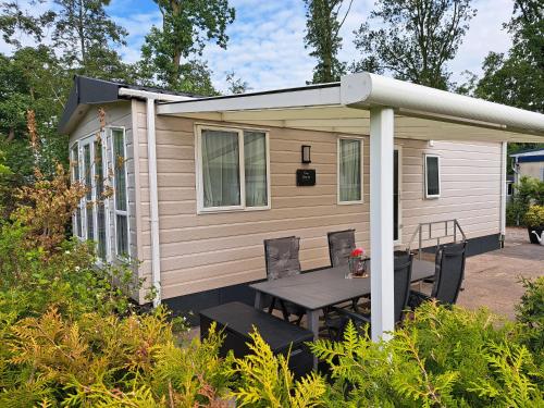 a tiny house with a table and a porch at Camping de Zandhorst, Chalet Victory in Wouterswoude
