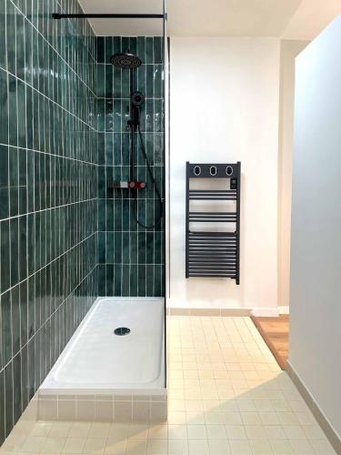 La salle de bains est pourvue de carrelage vert, d'une douche et d'une baignoire. dans l'établissement Fenêtre sur Cour - Albi Centre - Parking Privé, à Albi