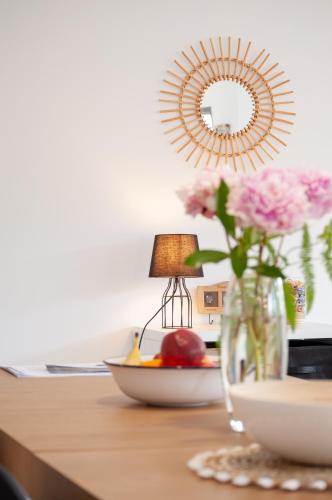 une table avec un vase de fleurs et un miroir dans l'établissement Maison St Brice Terrasse lits en 160 Confortable, à Arès