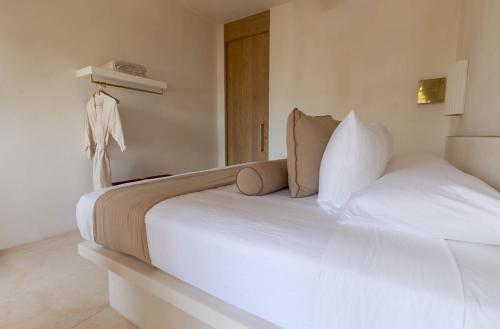 a bedroom with a large white bed with white pillows at Suites Panamera in Tulum