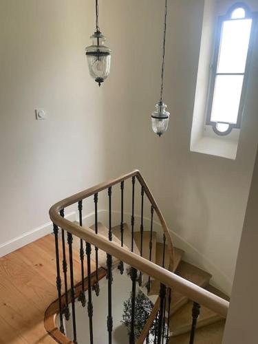a hallway with a staircase with a window and pendant lights at Gîte Glycine pour 8 personnes avec sauna et bain nordique in Capian