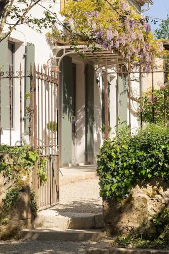 an entrance to a house with a gate with flowers at Gîte Glycine pour 8 personnes avec sauna et bain nordique in Capian