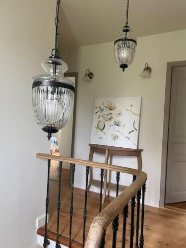 two chandeliers are hanging over a staircase in a room at Gîte Glycine pour 8 personnes avec sauna et bain nordique in Capian