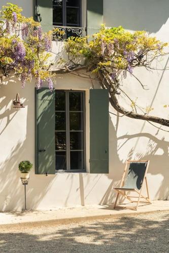 a building with a door and a window with purple flowers at Gîte Glycine pour 8 personnes avec sauna et bain nordique in Capian