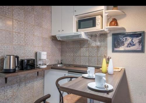 cocina con mesa de madera con sillas y microondas en Art Studio, en Chamonix-Mont-Blanc