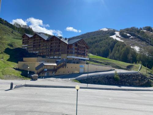 un grand bâtiment sur une colline avec un parking dans l'établissement La casa de la foux a proximité des pistes vue montagne 6 personnes Max, à Allos