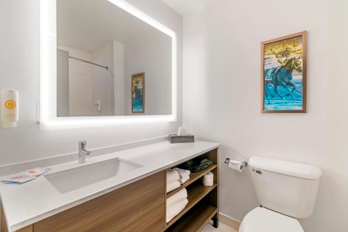 Baño blanco con lavabo y espejo en Comfort Inn & Suites Saratoga Springs, en Saratoga Springs