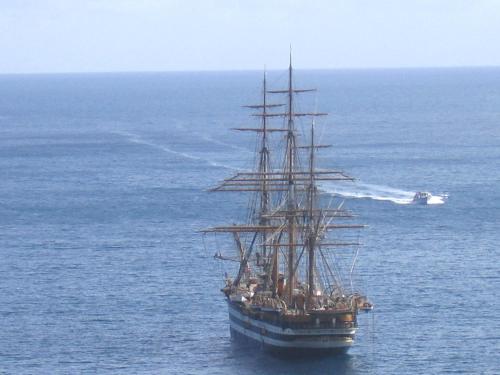 a tall ship in the ocean with a boat at La Camogliese Hotel B&B in Camogli