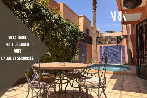 a table and chairs sitting next to a pool at Villa Targa Piscine 10 minutes du centre - ARK Realty in Marrakech
