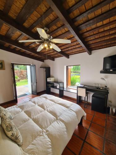 a bedroom with a large bed and a ceiling fan at Posada El Capullo in Colonia del Sacramento