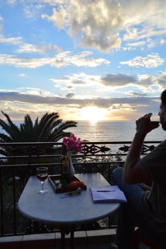 a man sitting at a table with a glass of wine at Mani Apartments in Agios Nikolaos