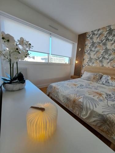 a bedroom with a bed and a vase of flowers on a table at Appartement de standing in Créteil