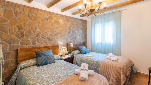 a bedroom with two beds and a stone wall at Rubito el Olmo Villanueva de la Concepción by Ruralidays in Villanueva de la Concepción