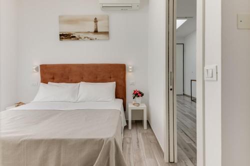 a bedroom with a large white bed with a wooden headboard at Residence Diffuso Arcobaleno in Gabicce Mare