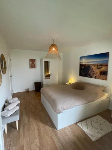 een witte slaapkamer met een groot bed en een stoel bij appartement Axelle 2 in Blankenberge