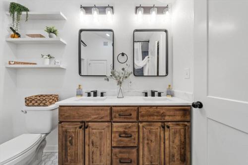 un baño con lavabo y dos espejos en JK'S Bungalow in Waco, en Waco