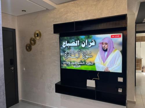 a television screen with a man on it in a room at Appartement Cosy Available in Kenitra