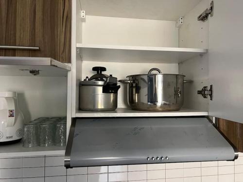 two pots and pans sitting on a shelf in a kitchen at Appartement Cosy Available in Kenitra
