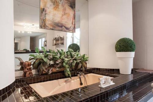 La salle de bains est pourvue d'un lavabo avec des plantes et d'un miroir. dans l'établissement Chambres d'hôtes de charme au REFUGE DU PEINTRE prés de St Emilion, à Sainte-Terre