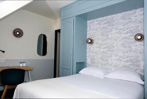 a bedroom with a bed with a blue headboard at The Originals City, Hôtel Armen Le Triton, Roscoff in Roscoff
