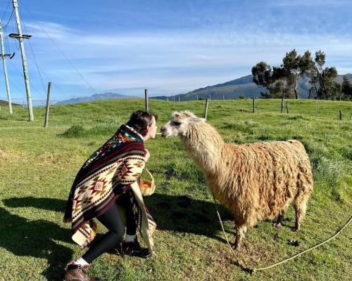 a woman is kissing a sheep in a field at Hacienda El Porvenir by Tierra del Volcan in Machachi
