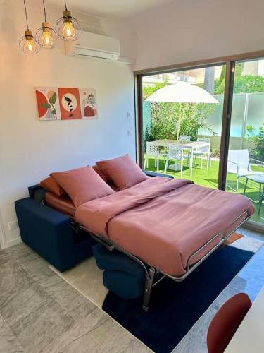 un grand lit dans une chambre avec une grande fenêtre dans l'établissement 2 pièces - Piscine - Terrasse XXL - Plage La Salis, à Antibes