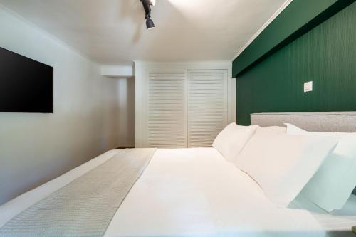 a bedroom with a white bed and a green wall at 4BD Apartment with Outdoor Jacuzzi Garden in Athens