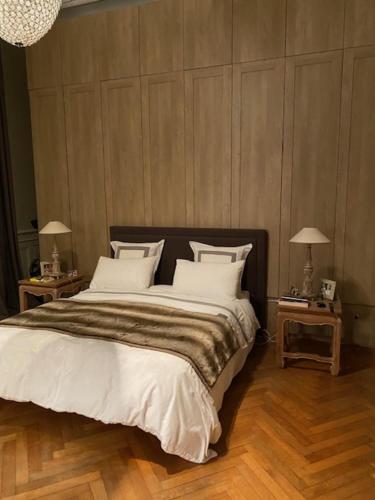 une chambre avec un grand lit avec des draps et des oreillers blancs dans l'établissement Appartement Bourgeois, à Bordeaux