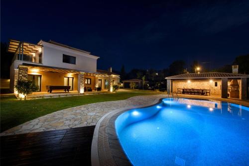 a swimming pool in front of a house at night at Villa Black White Dassia in Dassia