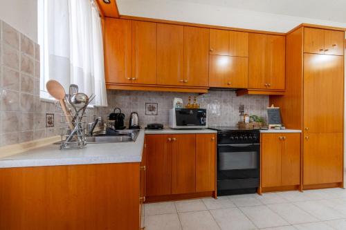 a kitchen with wooden cabinets and a sink and a stove at Mike's House in Kremasti near the Beach Rhodes in Kremasti