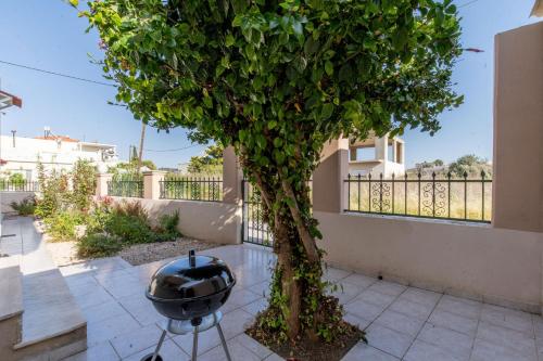 a grill sitting next to a tree on a sidewalk at Mike's House in Kremasti near the Beach Rhodes in Kremasti