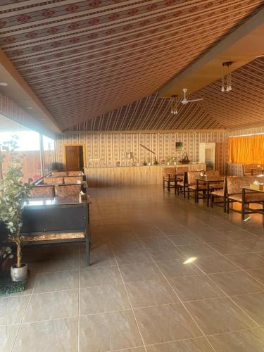 een grote kamer met houten plafonds en tafels en stoelen bij Wadi Rum Desert Bedouins in Wadi Rum