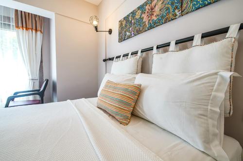 a bedroom with a white bed with pillows at Nirvana Hotel in Bozcaada