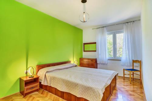 a green bedroom with a bed and a window at Apartman Meri in Cres