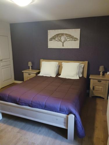 a bedroom with a bed with a tree on the wall at les accacias in Moyenmoutier