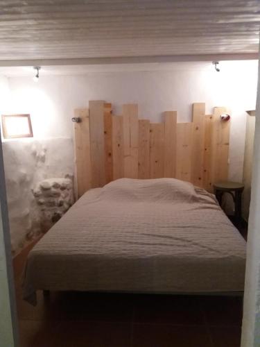 une chambre avec un lit avec une tête de lit en bois dans l'établissement Au coeur de la haute Provence, à Saint-Julien-dʼAsse