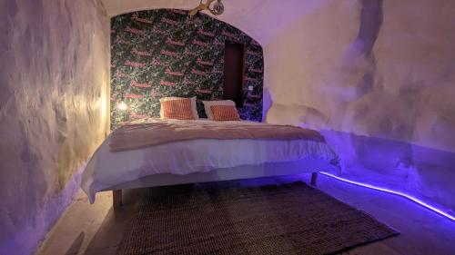 - une chambre avec un lit dans une pièce dotée de lumières violettes dans l'établissement SUITE Roch'amore troglodyte Romantique et Unique, à La Garde
