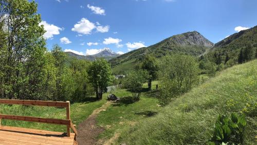 un banco de madera sentado en la cima de una colina con montañas en Le Domaine du Trappeur, en Saint-Sorlin-dʼArves