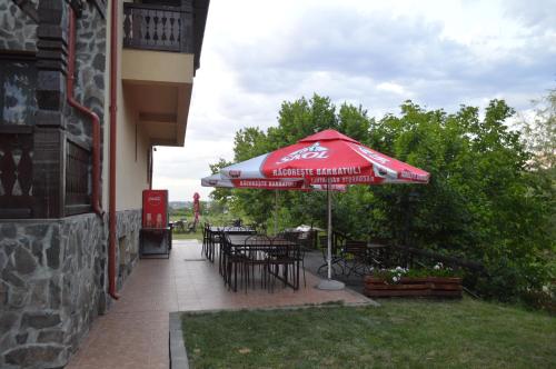 a patio with an umbrella and tables and chairs at Pensiunea VisAventura in Vişan