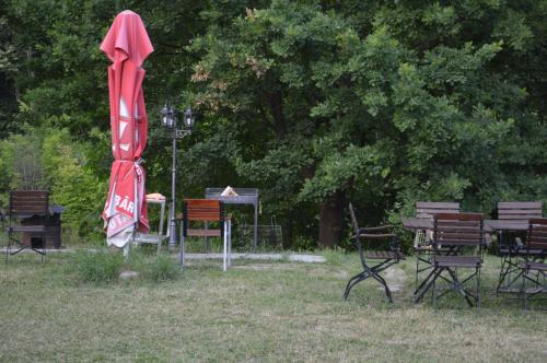 a group of tables and chairs and a red umbrella at Pensiunea VisAventura in Vişan
