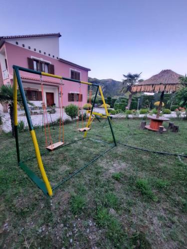 a group of swings in a yard with a house at Guesthouse Ndroq in Ndroq